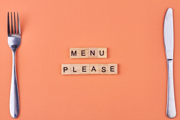 Menu please text written on wooden blocks Fork and knife on table