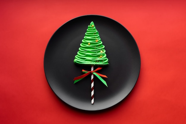 Merengue Christmas tree on a black plate. Red Christmas background.