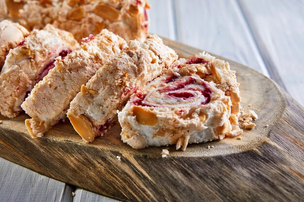 Merengue pie with pistachios and jam on a wooden board