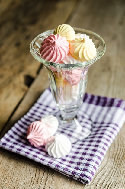 Meringue cookies in glass on rustic background