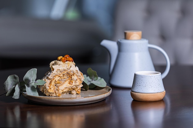 Photo meringue dessert on a ceramic plate next to a teapot with a cup