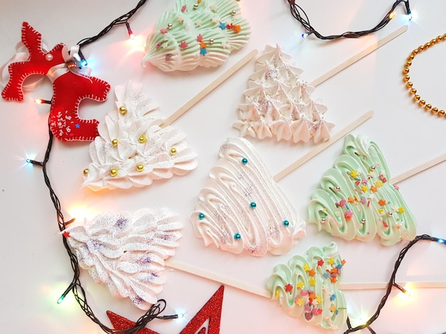 Meringue in the form of Christmas trees decorated with sprinkles. Christmas