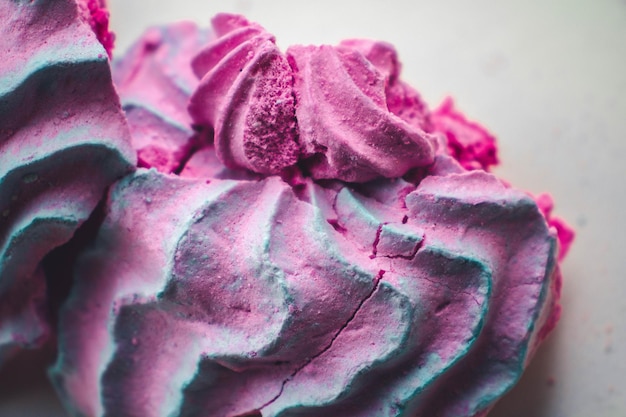 Meringue pale pink in the shape of a rose or flower meringue is a lot of cake decoration closeup