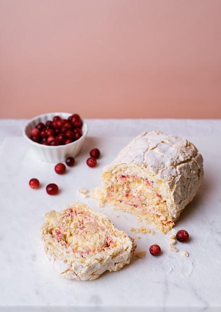 Meringue roll cake with cranberries on marble board