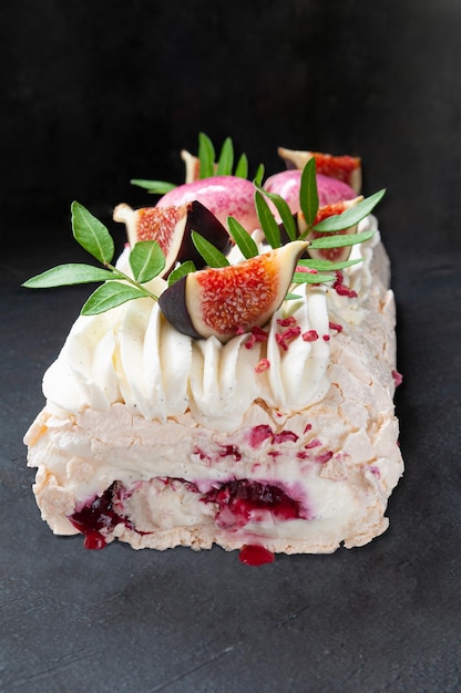 Meringue roll with cherry jam Decorated with greenery and fig slices Dark background