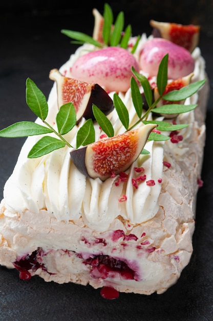 Meringue roll with cherry jam Decorated with greenery and fig slices Dark background