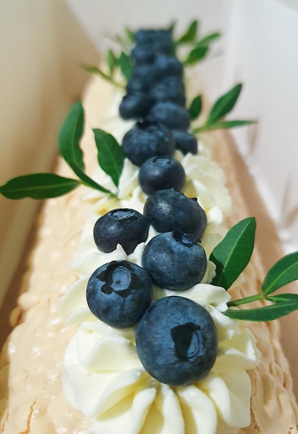 Meringue roll with a gentle airy cream green leaves and blueberries