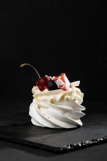 Meringue with berries on top on black background