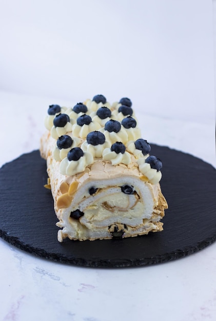 Meringuebroodje met bosbessen op een zwarte plaat Dessert op een witte achtergrond