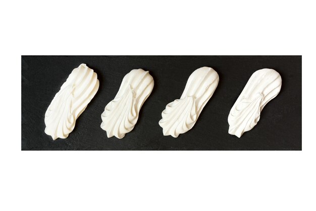 Meringues on a black tray isolated on white background