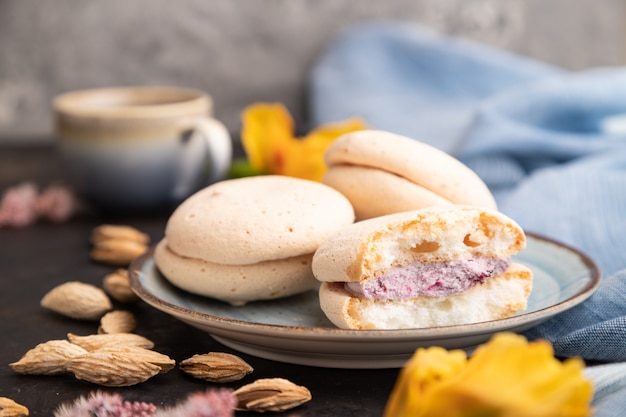 Meringues cakes with cup of coffee on a black concrete background. Side view, selective focus.