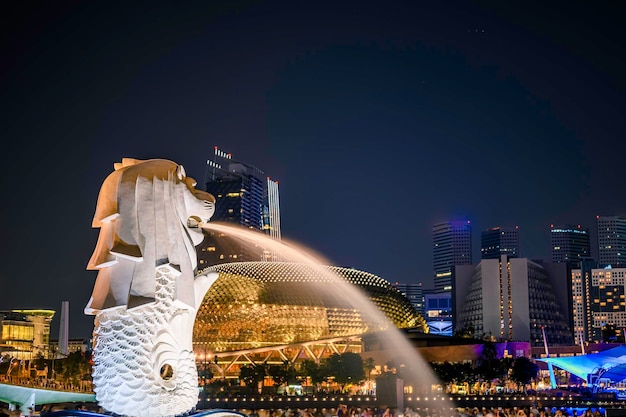Foto merlion-standbeeldfontein in merlion park en de stadshorizon van singapore bij nacht.