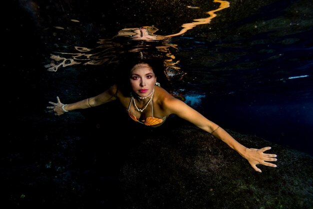 Foto sirena che nuota sott'acqua nel mare blu profondo