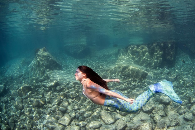 Русалка плавает под водой в глубоком синем море