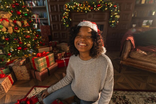 Merry christmas african american woman smiling near christmas tree in classical dark interior happy