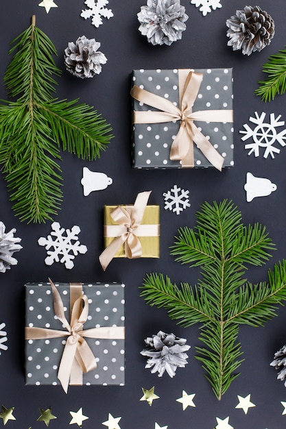 モミの枝、プレゼント、黒の装飾とメリークリスマスと幸せな新年のグリーティングカード