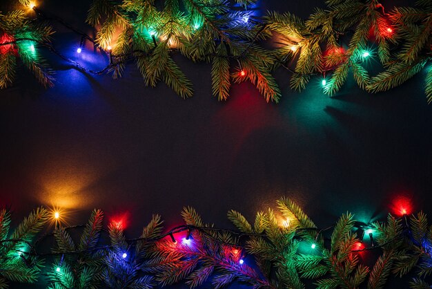 Merry Christmas background with copy space for text. New Year concept. Glowing fairy lights and decor of fir branches. Flat lay, top view