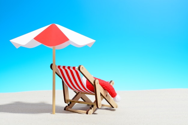 Merry Christmas on beach concept. Lounge chair with umbrella and Santa hat