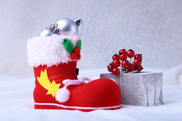 Merry Christmas composition. Santa's shoe with gift boxes on billowy feathers with snow and snowflakes. Happy holidays.