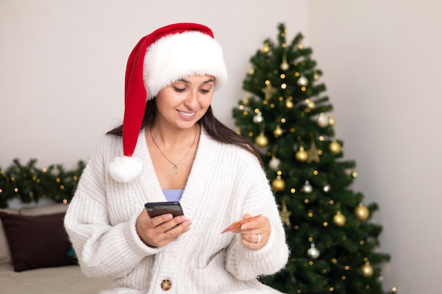 Foto merry christmas een mooie jonge vrouw doet aankopen op haar smartphone via internet betalen voor online winkelen lifestyle