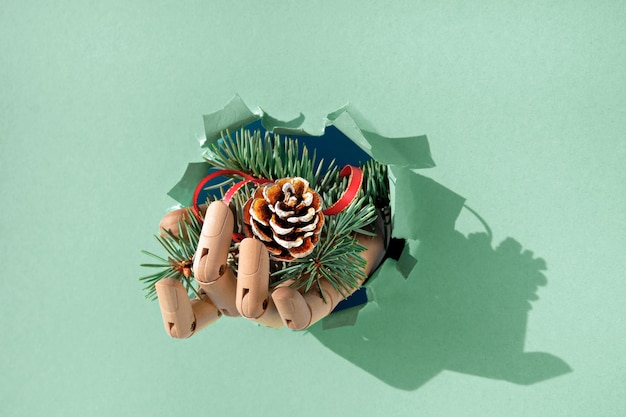 종이 구멍을 통해 전나무 잔가지와 원뿔이 있는 메리 크리스마스 손 창의적인 최소한의 개념 배경