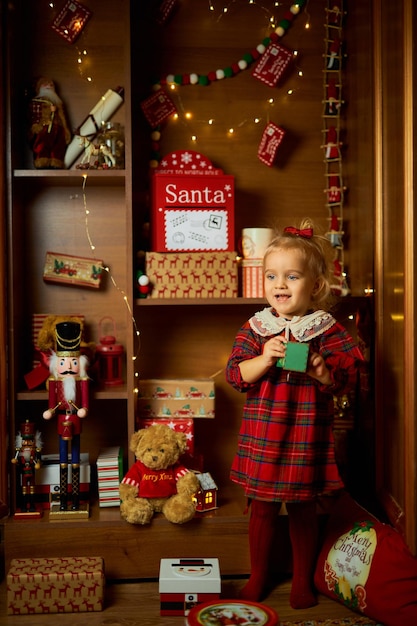 Photo merry christmas and happy holiday a little girl in a plaid dress