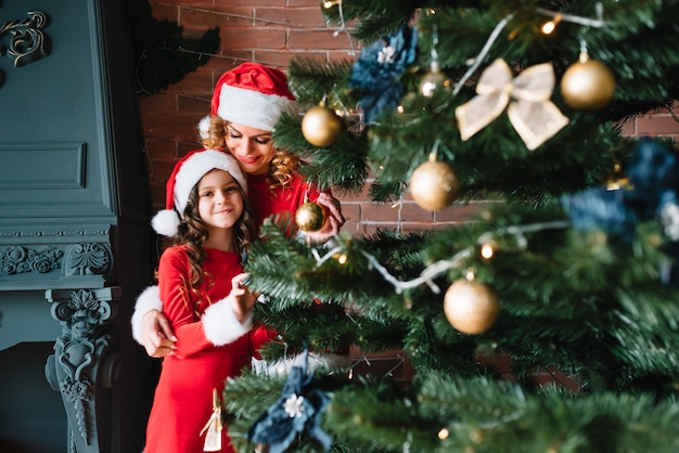 Merry Christmas and Happy Holidays! Beautiful mother with little daughter in Christmas costumes spend time together near the Christmas tree.