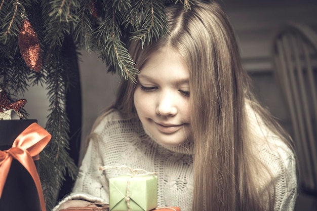 Merry Christmas happy holidays Cheerful cute little blonde girl opens a Christmas present