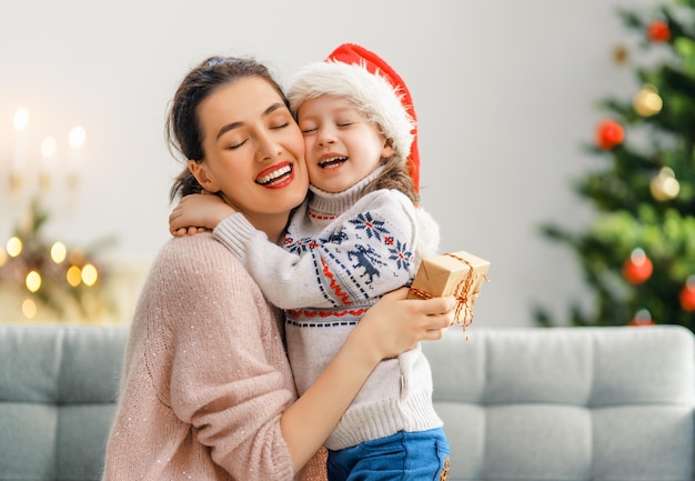 Merry Christmas and Happy Holidays Cheerful mom and her cute daughter girl exchanging gifts