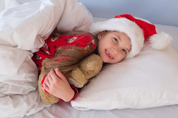 Merry christmas and happy holidays a cute smiling little girl of years old in a santa hat is lying