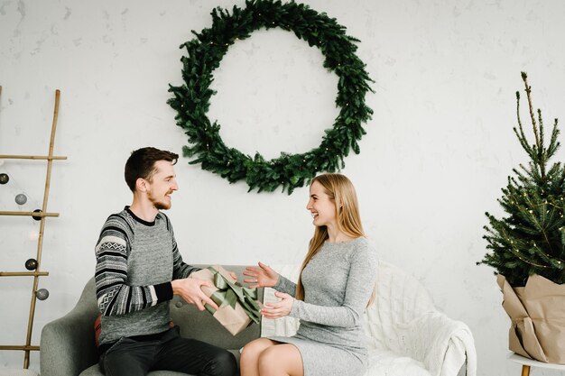 Merry Christmas and Happy Holidays. Man surprising his woman with a Christmas gift. Christmas couple with present. Happy New Year 2021.