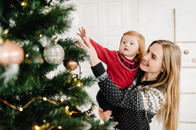 Merry Christmas and Happy Holidays Mom and daughter decorate the Christmas tree at home