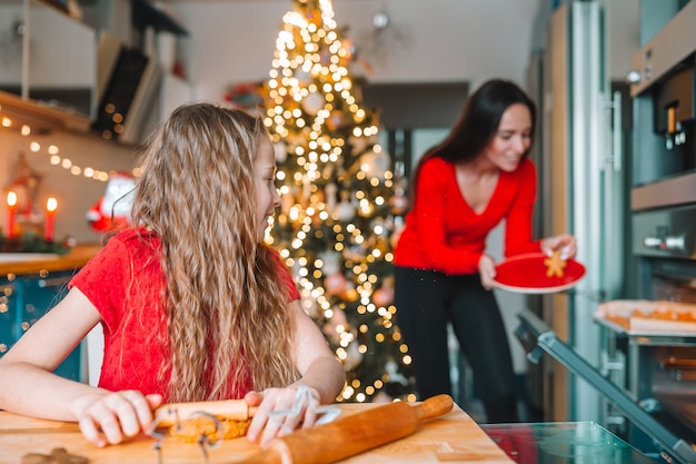 Merry Christmas and Happy Holidays. Mother and her daughters cooking Christmas cookies on the kitchen