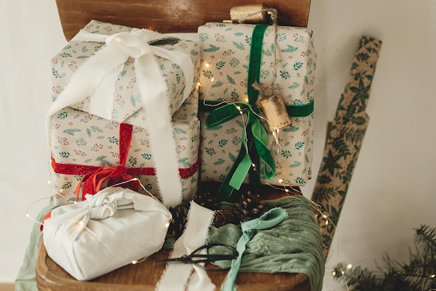 メリー クリスマスとハッピー ホリデー 田舎の部屋の古い木の椅子のお祝い紙とトウヒの枝にリボンが付いたスタイリッシュなラップ クリスマス ギフト環境に優しいプレゼント