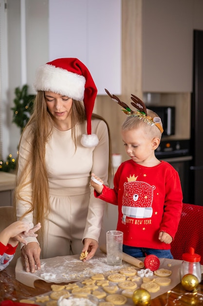 Merry Christmas. Happy Mom with children son bake Christmas cookies. Kitchen at home. Festive atmosphere High quality photo