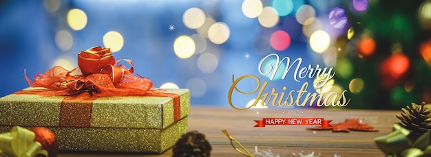 Merry christmas and happy new year banner for head or cover of\
social media website or fan page decorative. golden gift box with\
red bow tie with blessing xmas text and light bokeh.