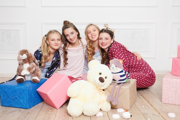 メリークリスマスと新年あけましておめでとうございますクリスマスツリーで家で奇跡を待っているパジャマ姿の美しい幸せな4人の子供の女の子。クリスマスのギフトボックスを持つ小さな笑顔の女の子。休日、人々の概念。