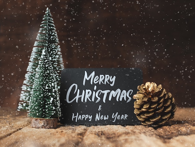 Merry Christmas and happy new year on blackboard with xmas tree and gold pine cone 