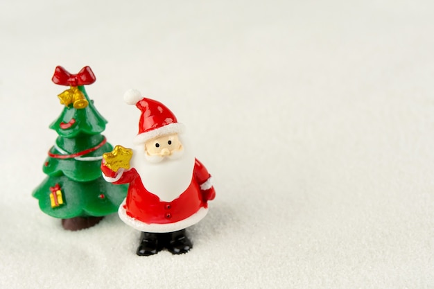 メリークリスマスと新年あけましておめでとうございますのコンセプト。かわいいサンタクロースの図とコピースペースと雪の上の木