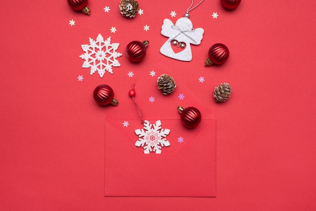 Buon natale e felice anno nuovo concetto. in alto sopra l'immagine fotografica ravvicinata di una busta luminosa di colore rosso non imballata e accessori per le vacanze che volano via sul tavolo rosso