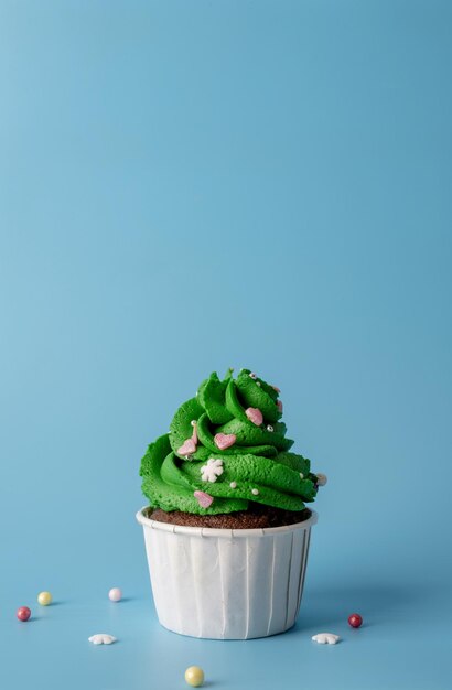 merry christmas and happy new year. green christmas tree shaped cupcakes on blue background. minimal style, copy space