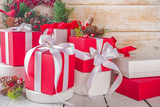 즐거운 성탄절 보내시고 새해 복 많이 받으세요. 노엘 인사말 카드 배경입니다. 세련된 흰색 연단에 축제 리본이 있는 크리스마스 선물 상자, 제품을 위한 공간, 나무 배경