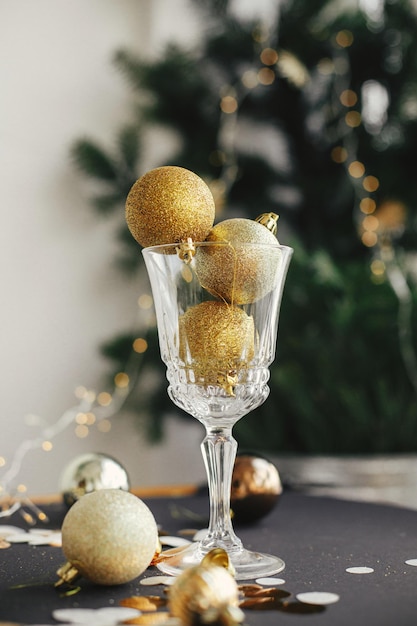 Foto buon natale e felice anno nuovo eleganti palline di natale glitterate in bicchiere di champagne e decorazioni dorate sul tavolo scuro composizione creativa per la festa di capodanno banner lunatico per le vacanze
