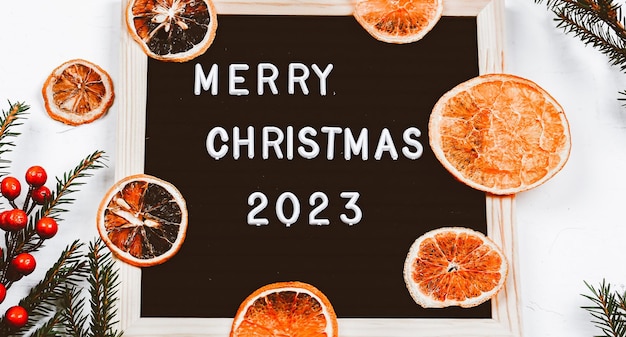 Merry Christmas-letters op letterbord Sparren takken en gedroogde sinaasappelen minimalistische nieuwjaarsachtergrond 2023