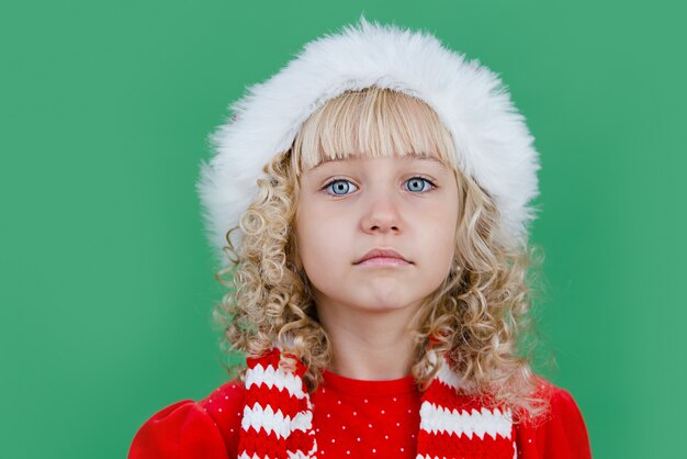 Merry Christmas Little girl in Santa hat on bright green