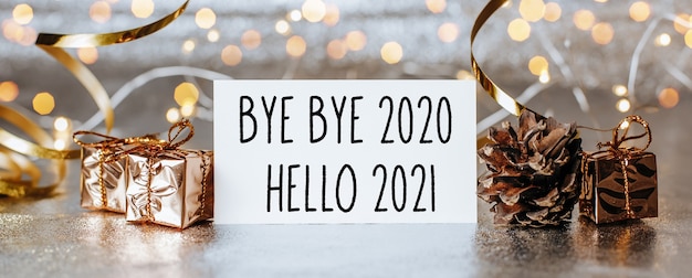 Photo merry christmas and merry new year concept with gift boxes and greeting card with text bye bye 2020 hello 2021