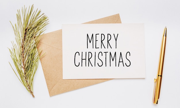 Merry christmas note with envelope, spruce branch and gold pen on white background. merry christmas and New Year concept