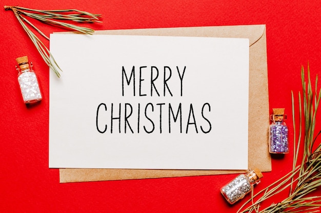 Merry christmas note with gift, fir branch and toy on red isolated background. New Year concept