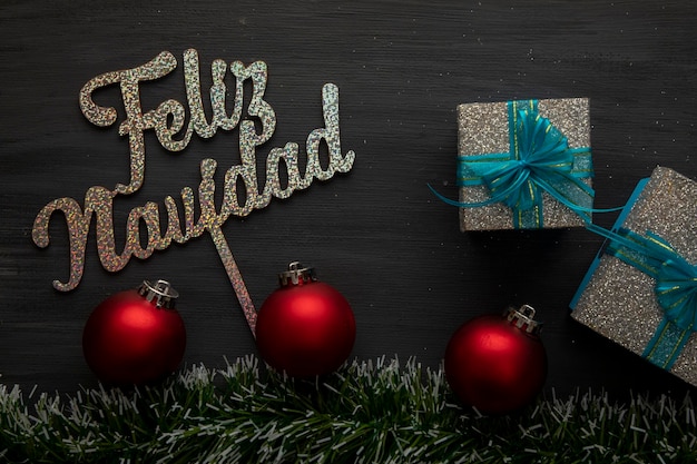 Merry christmas sign with spheres and gifts on black background