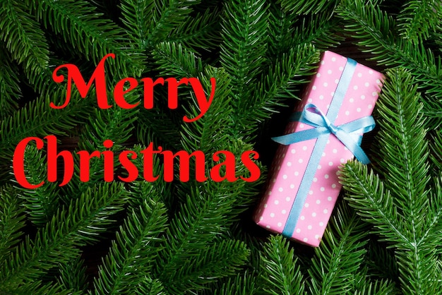 Merry Christmas text Top view of Christmas gift box on fir tree background Time for holiday concept with copy space